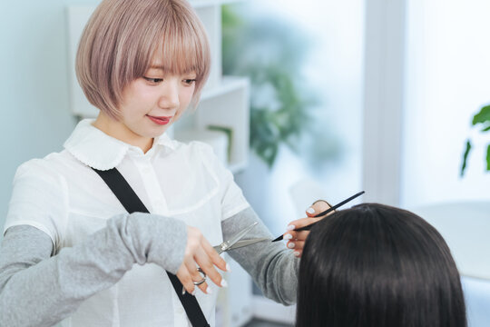 ヘアカットするハイトーンヘアの女性スタッフ