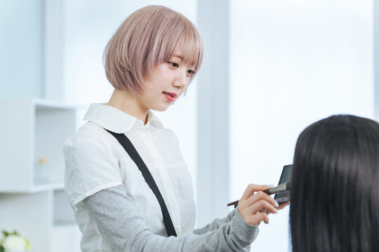 メイクするハイトーンヘアの女性スタッフ
