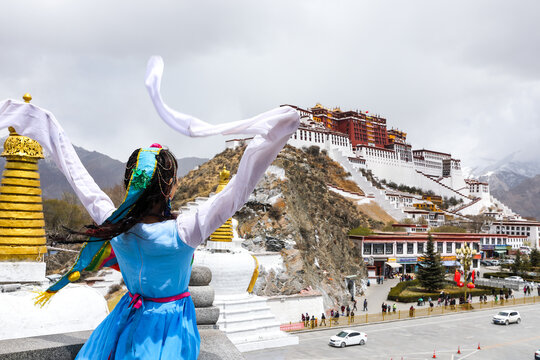 Woman in traditional Tibetan dress facing Potala Palace, Lhasa Tibet