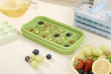 Fruit tea ice cubes with berries and grapes in silicone tray on kitchen counter © TrinhBaoTran