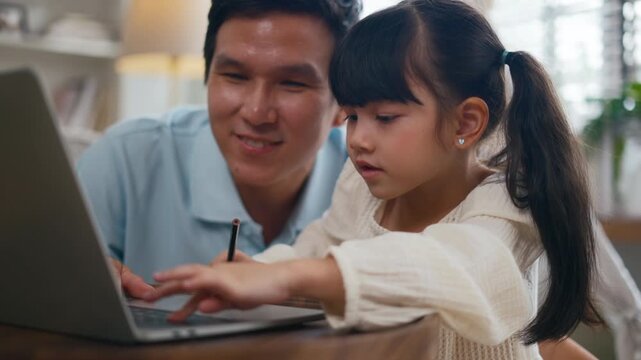 Asian father teaching daughter doing homework,online learning on laptop computer at home.Parents homeschooling and supporting girl during summer break.Concept of online education and online learning