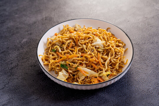 Javanese fried noodles or Bakmi Jawa served in a bowl on dark background, traditional Indonesian noodle dish with vegetables and savory flavor