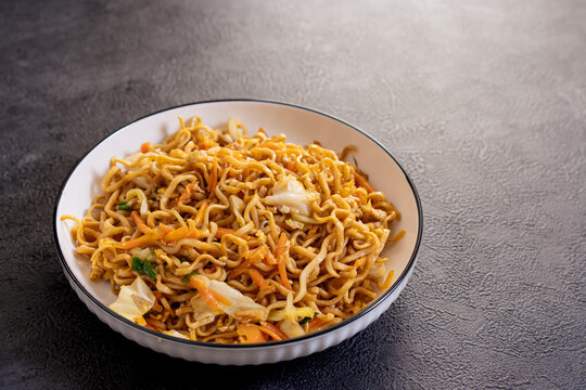 Close up  - Javanese fried noodles or Bakmi Jawa served in a bowl on dark background, traditional Indonesian noodle dish with vegetables and savory flavor