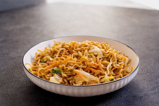 Javanese fried noodles or Bakmi Jawa served in a bowl on dark background, traditional Indonesian noodle dish with vegetables and savory flavor