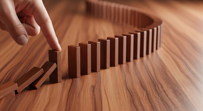Wooden dominoes in a curved line being triggered by a human finger for business strategy concept