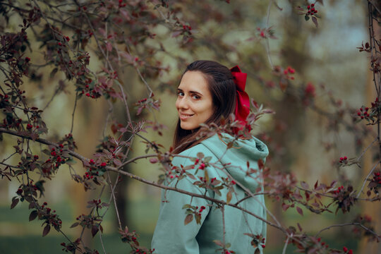 Woman with a Red Bow in Her Hair Enjoys Spring Nature. Beautiful lady glancing at the camera looking relaxed and peaceful 