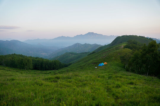 Peaceful camping scene on a green mountain at dawn
