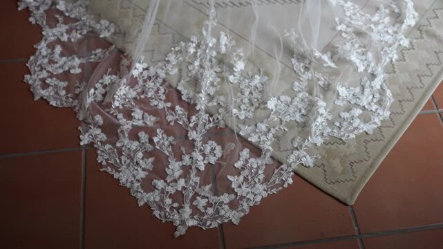 White tulle bridal veil with floral lace appliqu&eacute; border on tiled floor