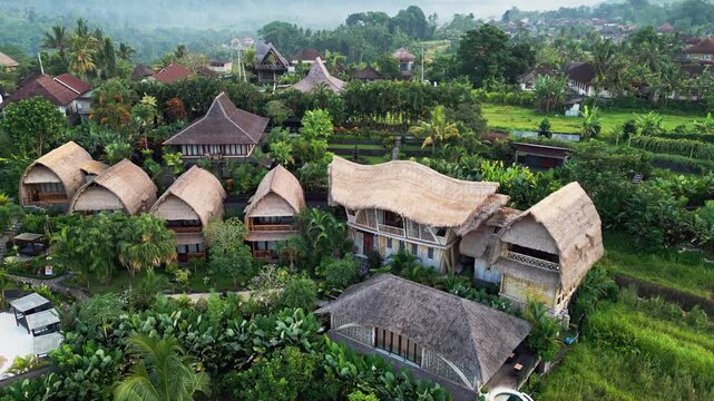 Aerial drone view of tropical resort with bamboo villas surrounded by lush greenery and tropical garden creating a peaceful luxury escape in a scenic countryside landscape