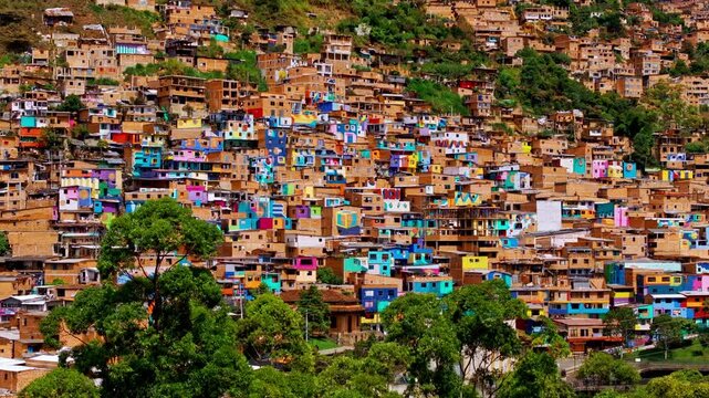 Aerial drone view of colorful hillside homes in Medell&iacute;n, Colombia, showcasing dense urban layers, vibrant architecture, and the city&rsquo;s distinctive residential landscape from above.