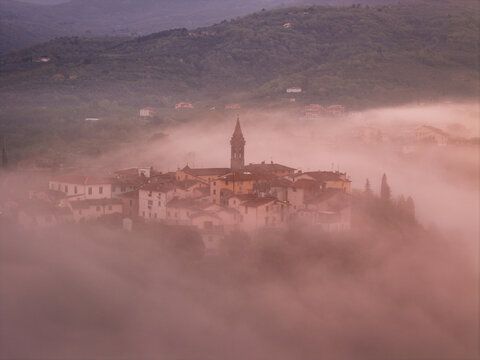 Aerial view of the historic village of Piantravigne with its church steeple rising above a thick blanket of morning fog in Piantravigne, Tuscany, Italy.
