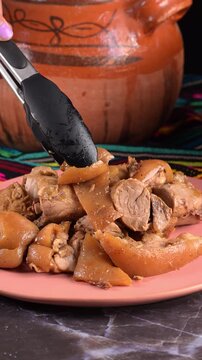 Place a piece of juicy pork carnitas and fried skin (cuerito) on a rustic table. Traditional Mexican food