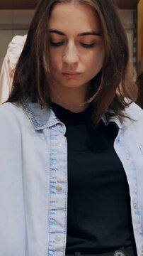 Woman examining clothing. Contemplative woman inspecting fabric. Woman carefully checking garment details and fit. Female shopper thoughtfully assessing shirt for wrinkles and seams