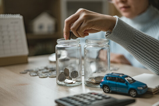 Person putting coins into jars for emergency fund, representing savings planning, financial security, risk management, and personal finance preparation for future expenses and unexpected situations.