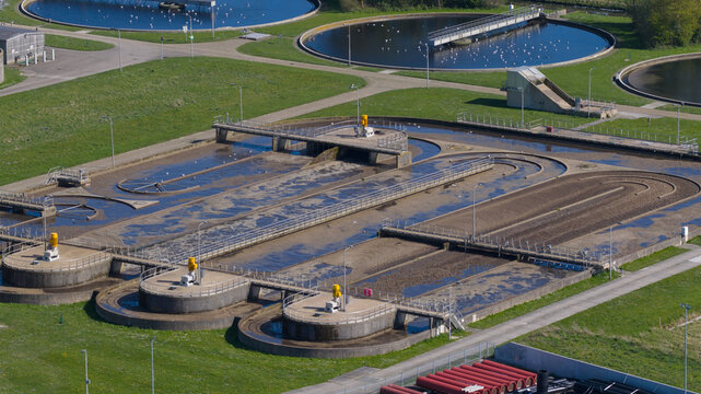 Aerial view of the RWZI Geestmerambacht wastewater treatment plant with circular aeration tanks and industrial filtration systems in Warmenhuizen, Noord-Holland, Netherlands.