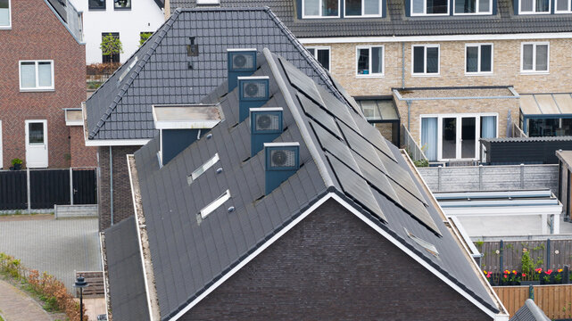 Aerial view of modern residential rooftops in the Nobelhorst neighborhood featuring solar panels and heat pump units in Almere, Flevoland, Netherlands.
