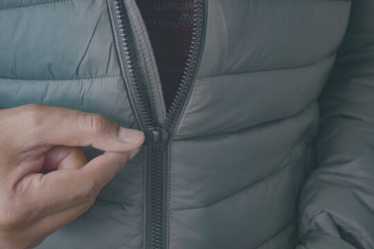 Person zipping up a gray jacket outdoors in winter