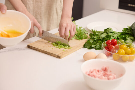 Hands chopping celery on cutting board in home kitchen during meal preparation