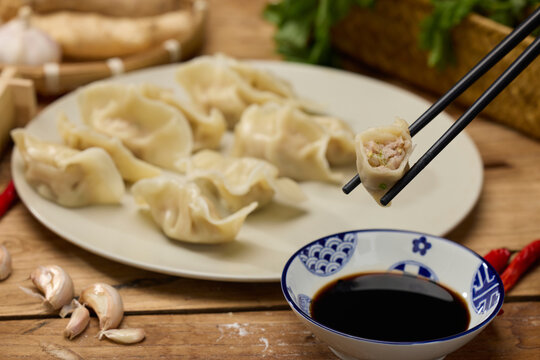 Boiled dumplings with soy vinegar dipping sauce and chopsticks on rustic table
