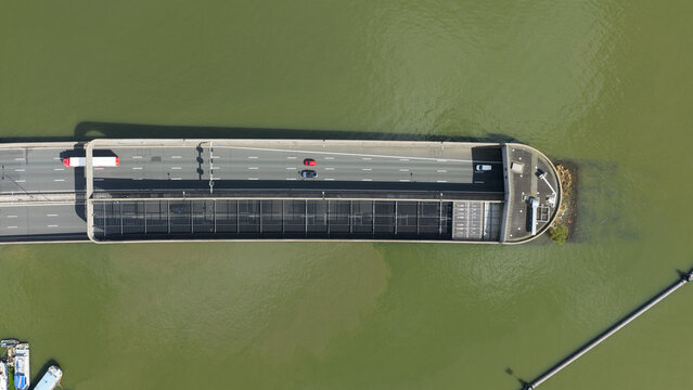 Aerial view of the Zeeburgertunnel entrance with cars driving on the highway over the green water of the IJ river in Amsterdam, Noord-Holland, Netherlands.