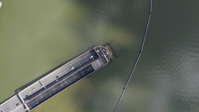 Aerial view of the Zeeburgertunnel entrance with cars driving on the highway as it emerges from the IJ river water Amsterdam, Noord-Holland, Netherlands.