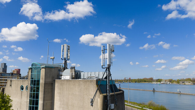 Aerial view of telecommunication antennas on a modern building at Zuider IJdijk overlooking the water under a blue sky with clouds in Amsterdam, Noord-Holland, Netherlands.