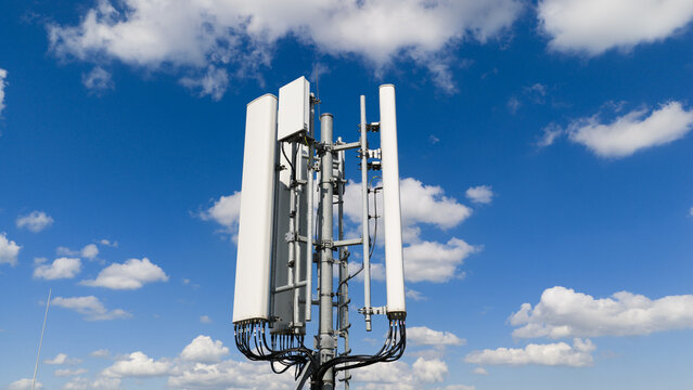 Aerial view of telecommunication antennas and cellular equipment on a mast against a blue sky with white clouds in Amsterdam, Noord-Holland, Netherlands.