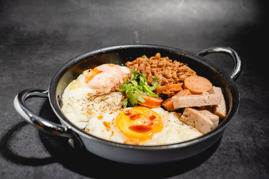 Thai-style pan-fried eggs with Chinese sausage, Vietnamese sausage, and seasoned minced pork, drizzled with sauce in a small pan.