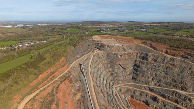 Aerial view of Old Cliffe Hill quarry showing terraced rock faces and industrial conveyor belts surrounded by green fields and hills in Stanton under Bardon, England, United Kingdom.