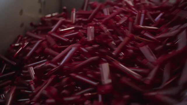Close-up of red PET plastic preforms used for bottle production in an industrial manufacturing facility. Raw materials for plastic packaging before blow molding process.