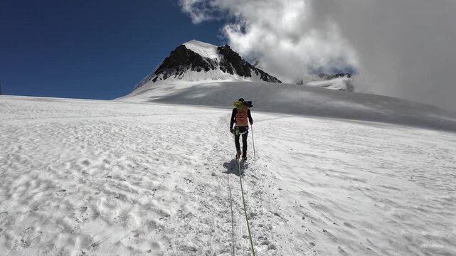 POV mountaineering in rope team with mountaineer and mountain panorama with summit Pollux on the glacier in summer in Pennine Alps, Italy
