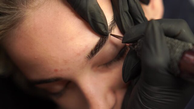 Permanent makeup hair stroke technique close up, eyebrow micropigmentation procedure with machine and pigment