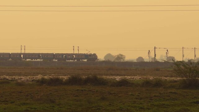 local train moving on rail tracks from a farm field in india