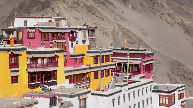 Thiksey Monastery perched on a hill in Ladakh, India, with colorful traditional Tibetan Buddhist architecture. Smooth backward pullback reveals the complete monastery complex against mountain backdrop