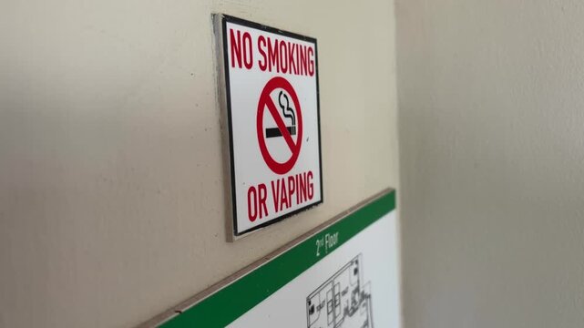 No smoking and no vaping sign on wall showing prohibition symbol in public indoor area