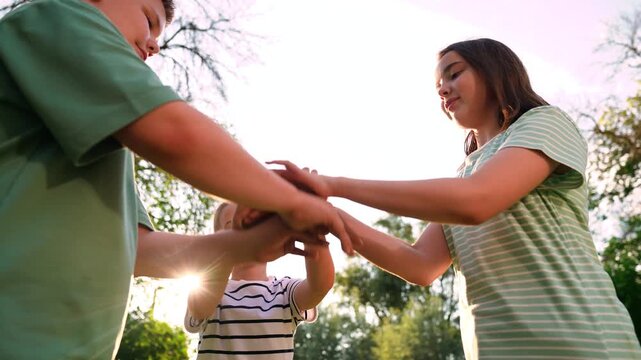 Happy children playing playground, children hands sun glare nature, boy girl friends playground, carefree childhood scene in a green park, active kids enjoying sunshine and movement, playful kids