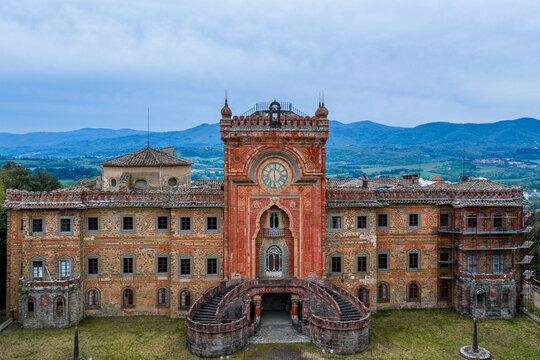 Aerial view of Sammezzano Castle with its ornate Moorish architecture, intricate facade patterns, and grand entrance staircase under a cloudy sky in Reggello, Tuscany, Italy.