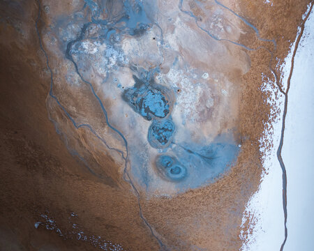 Aerial view of geothermal mud pools and steaming vents in the volcanic landscape of Myvatn with snow-covered ground Thingeyjarsveit, Iceland.