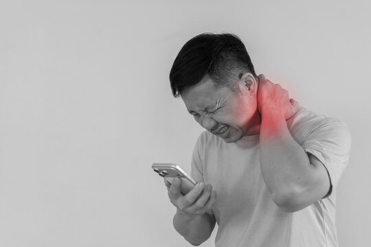 Asian man with highlighted neck pain using smartphone in monochrome portrait