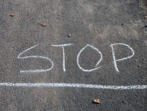 white stop sign word written on road surface