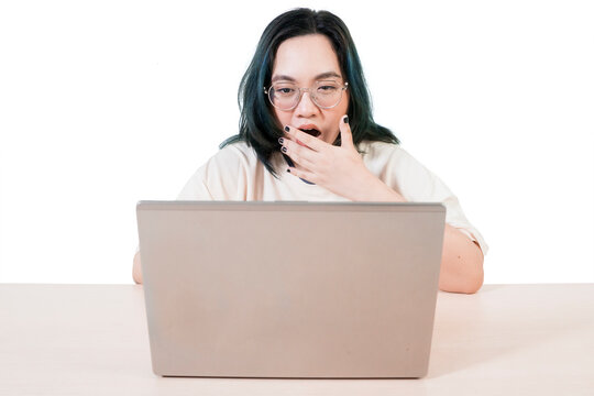 Shocked Young Woman Looking at Laptop Screen with Hand Over Mouth Against White Background