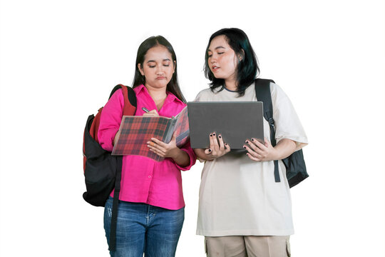 Two Young Female Students Collaborating and Studying Together with Laptop and Notebook