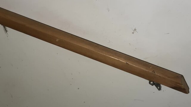 Wall mounted wooden handrail with metal support bracket along staircase showing interior structure and home safety detail