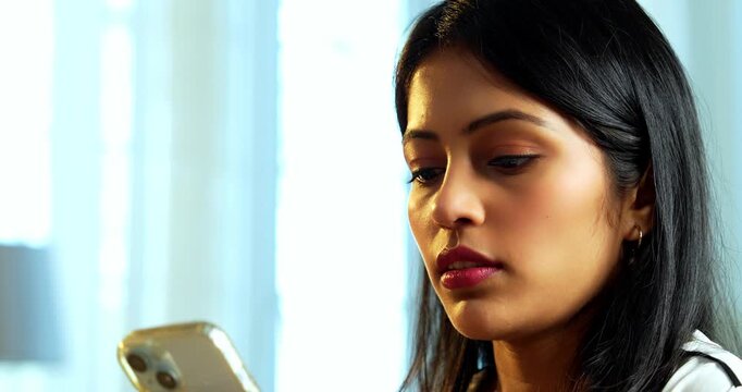 Indian young business lady getting irritated with spam call on her smartphone at workplace