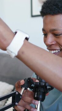 Vertical video: Checking mic boom, man on couch in blue tee speaking for recording, showing watch
