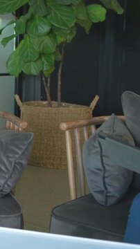 Vertical video: Arriving cohost moving mic woman yellow specs holding tablet recording in lounge