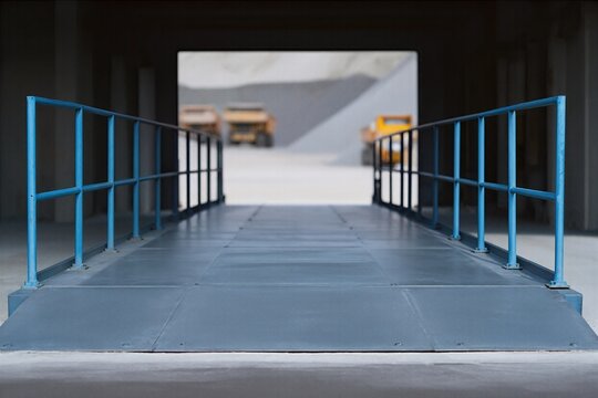 Quarry weighbridge deck with blue guard rails in industrial setting