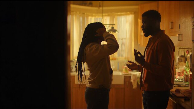 Silhouetted shot of a young adult Black man and woman worried and in tension standing together in a moody atmospheric setting, perfect for dramatic cinematic storytelling.