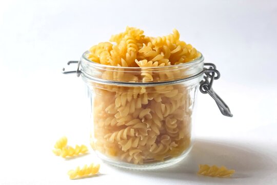 fusilli pasta in a glass jar isolated on a white background