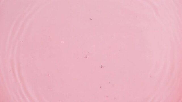 ピンク色の水面に広がる柔らかな波紋と抽象的な背景テクスチャ